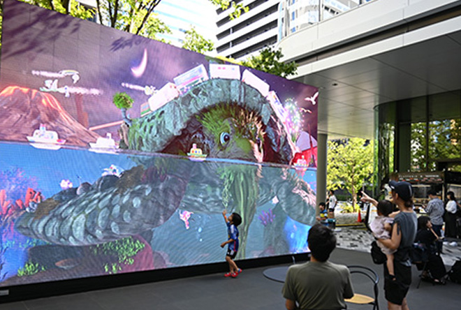 来場者の⽬を惹く300インチの⼤型LEDディスプレイはイベント情報と⼦どもが遊べる「未来のお絵描き」コンテンツを切り替えて表⽰できる